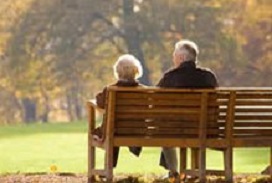Photograph of older couple sitting on a bench in a park